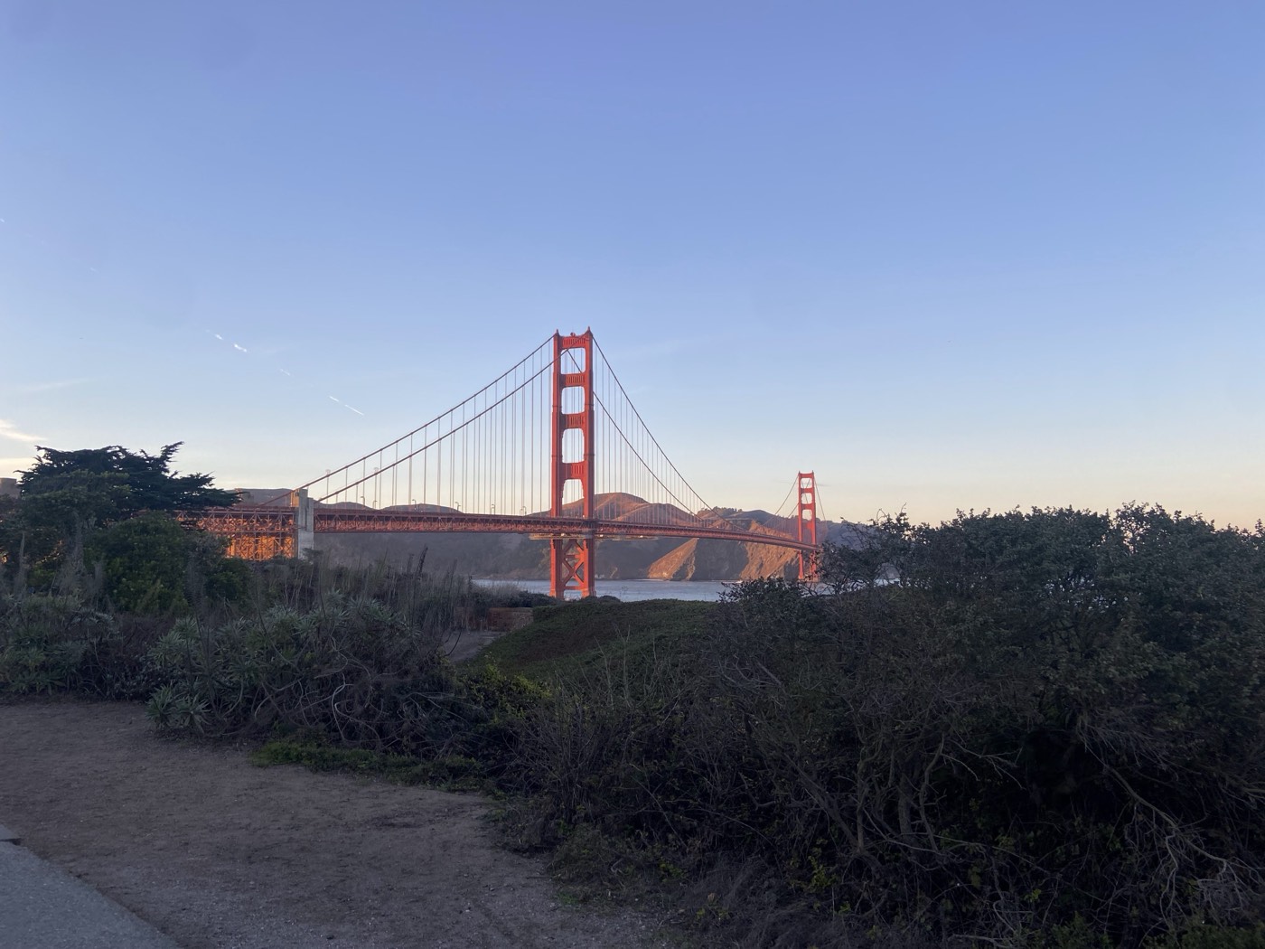 The Golden Gate Bridge at golden hour, seen from a coastal trail in San Francisco